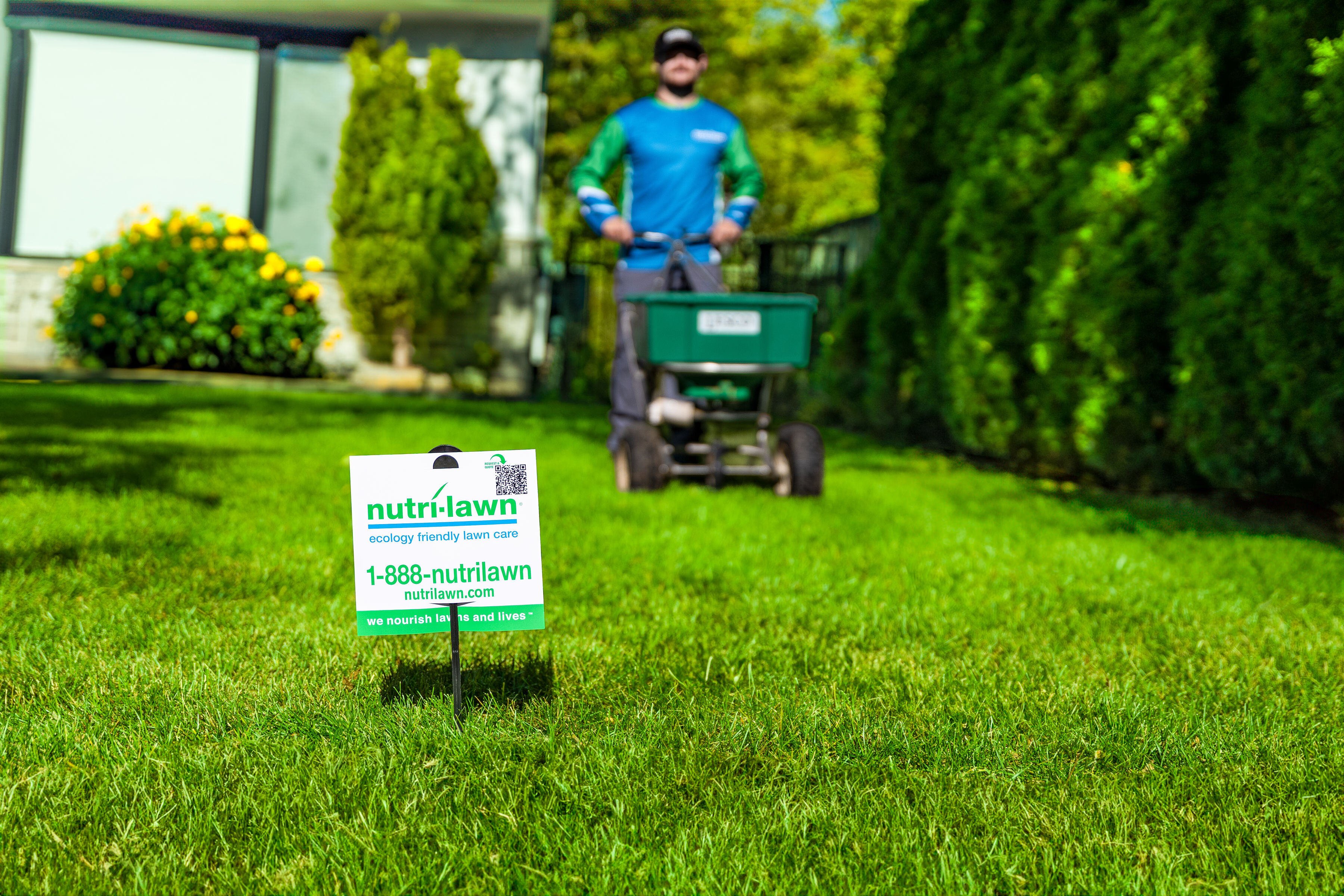 Professional lawn care service applying fertilizer and weed control treatment on residential lawn